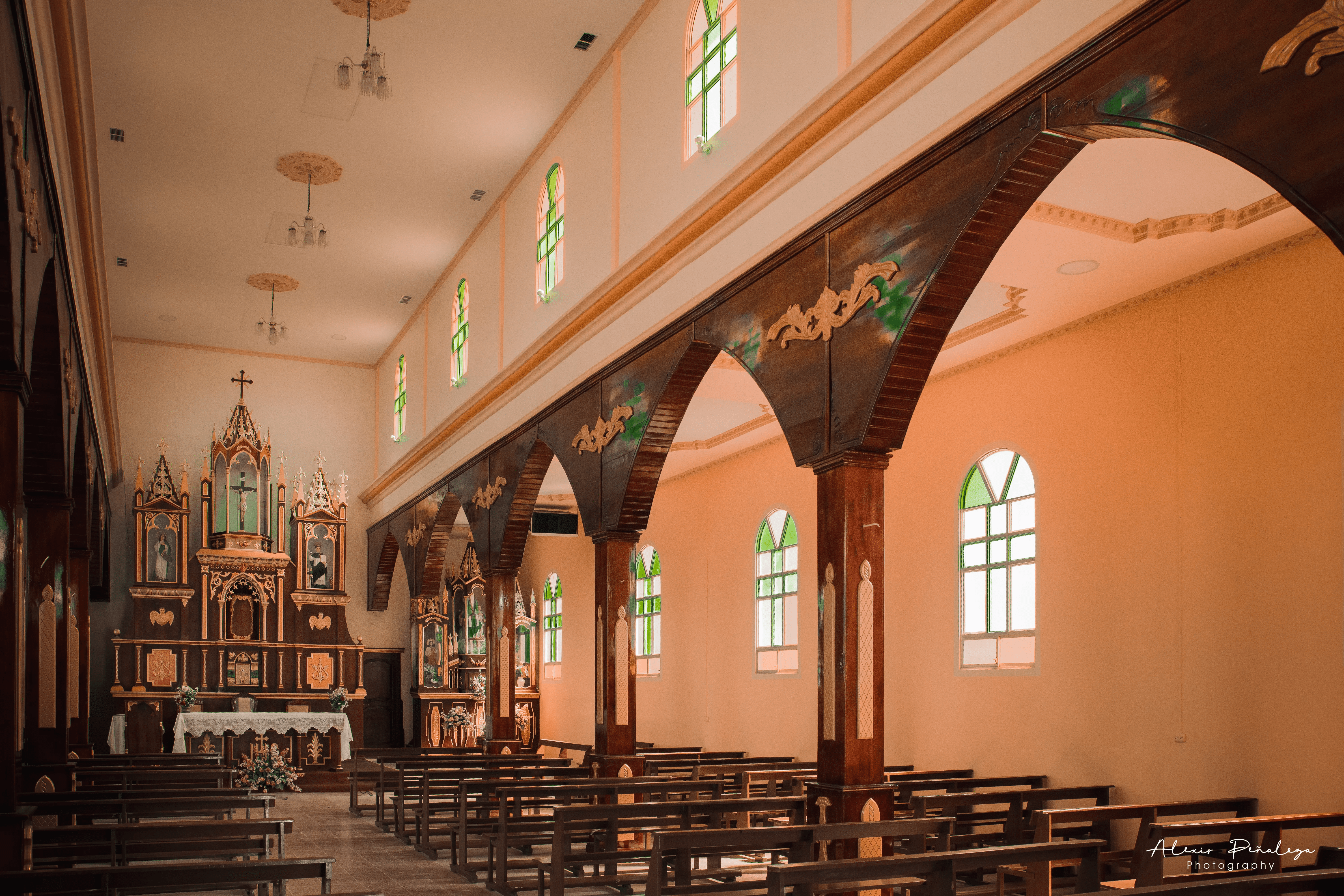 Sucesión de robustos arcos de madera oscura a lo largo del pasillo lateral