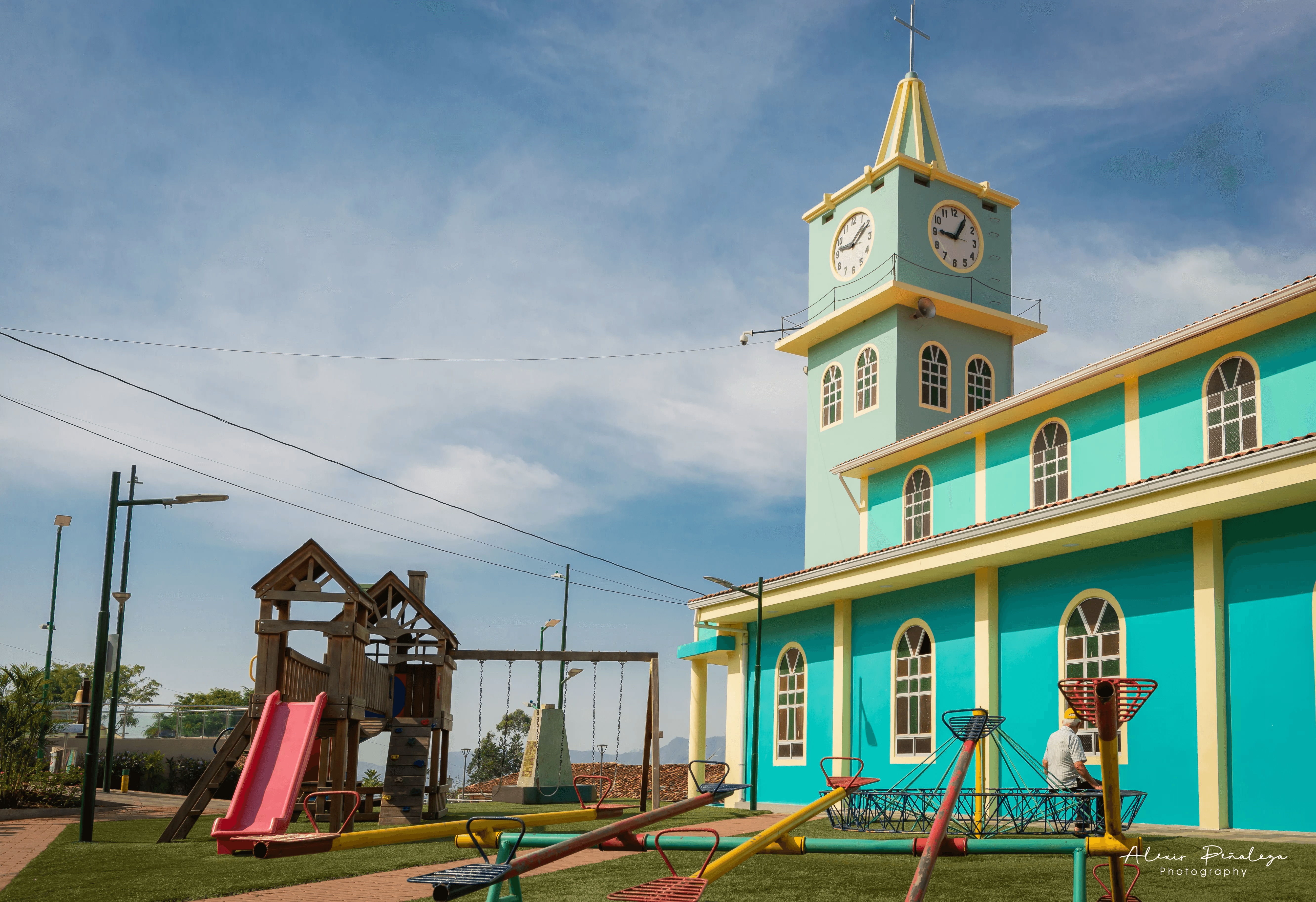 Hombre descansando en el parque junto a los juegos infantiles y la iglesia