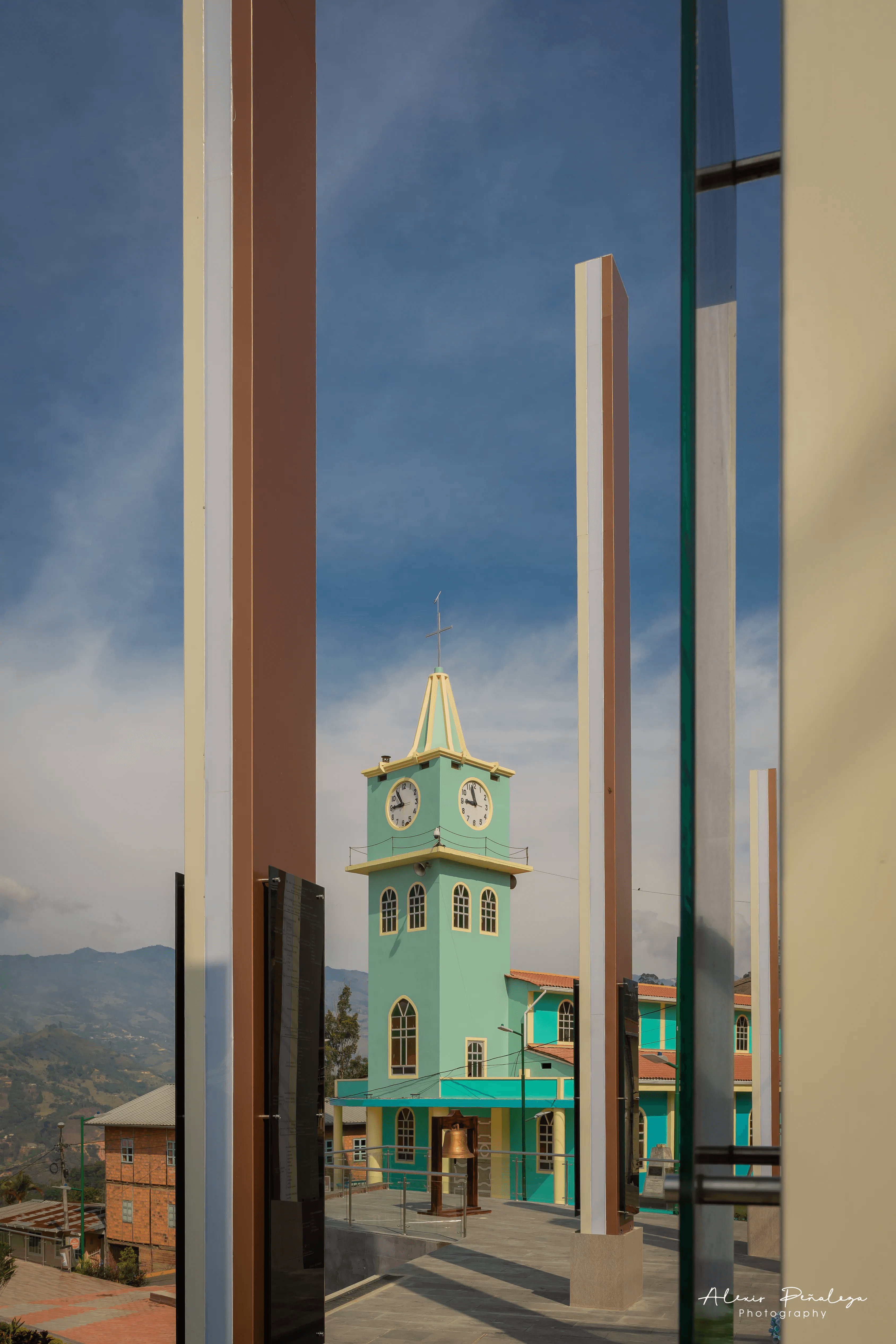 La torre de la iglesia a través de las columnas del parque
