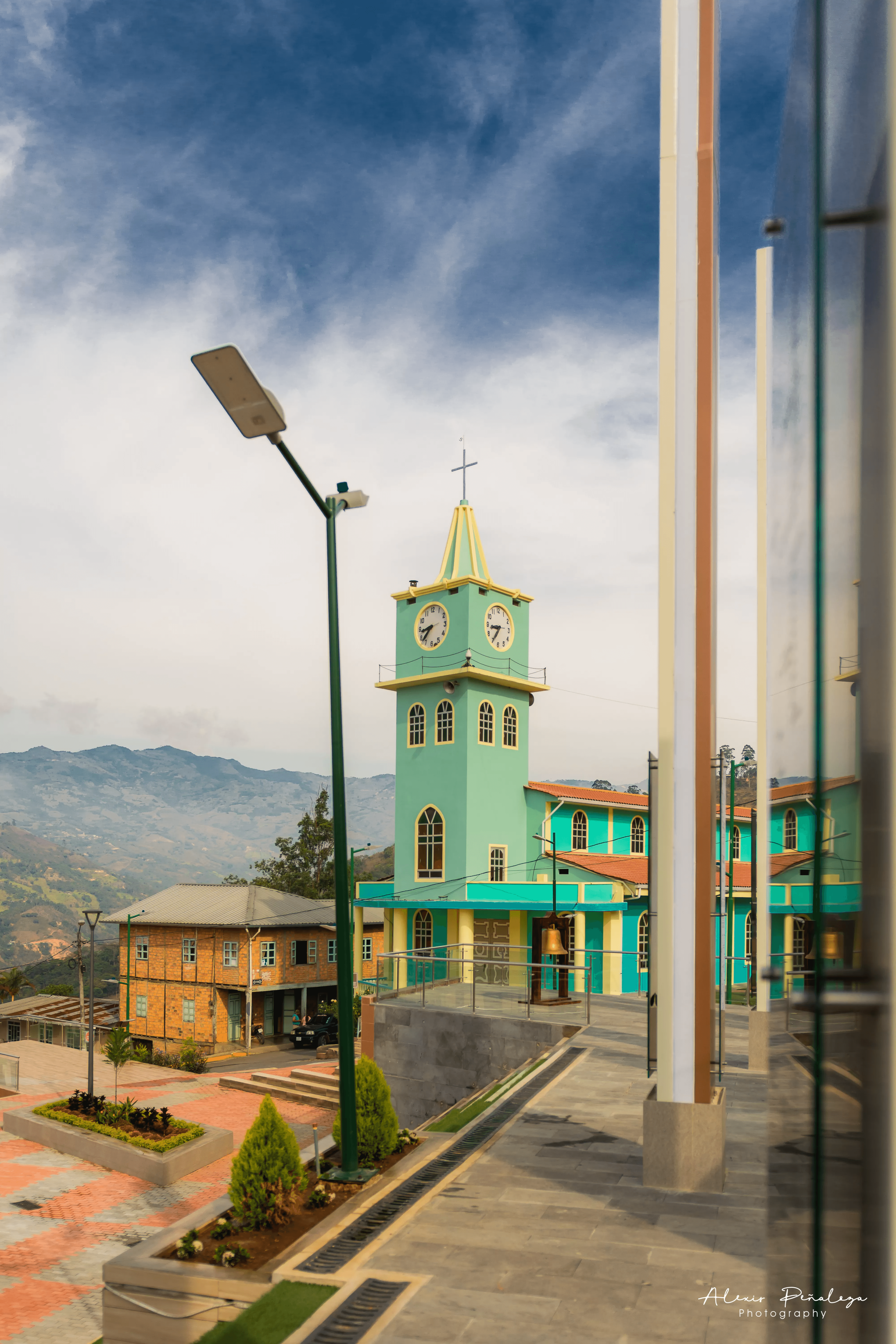 Iglesia turquesa y farol en la plaza principal de Muluncay