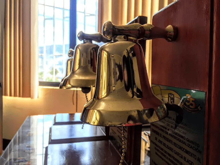 Campanas doradas decorativas sobre un escritorio iluminado junto a una placa conmemorativa