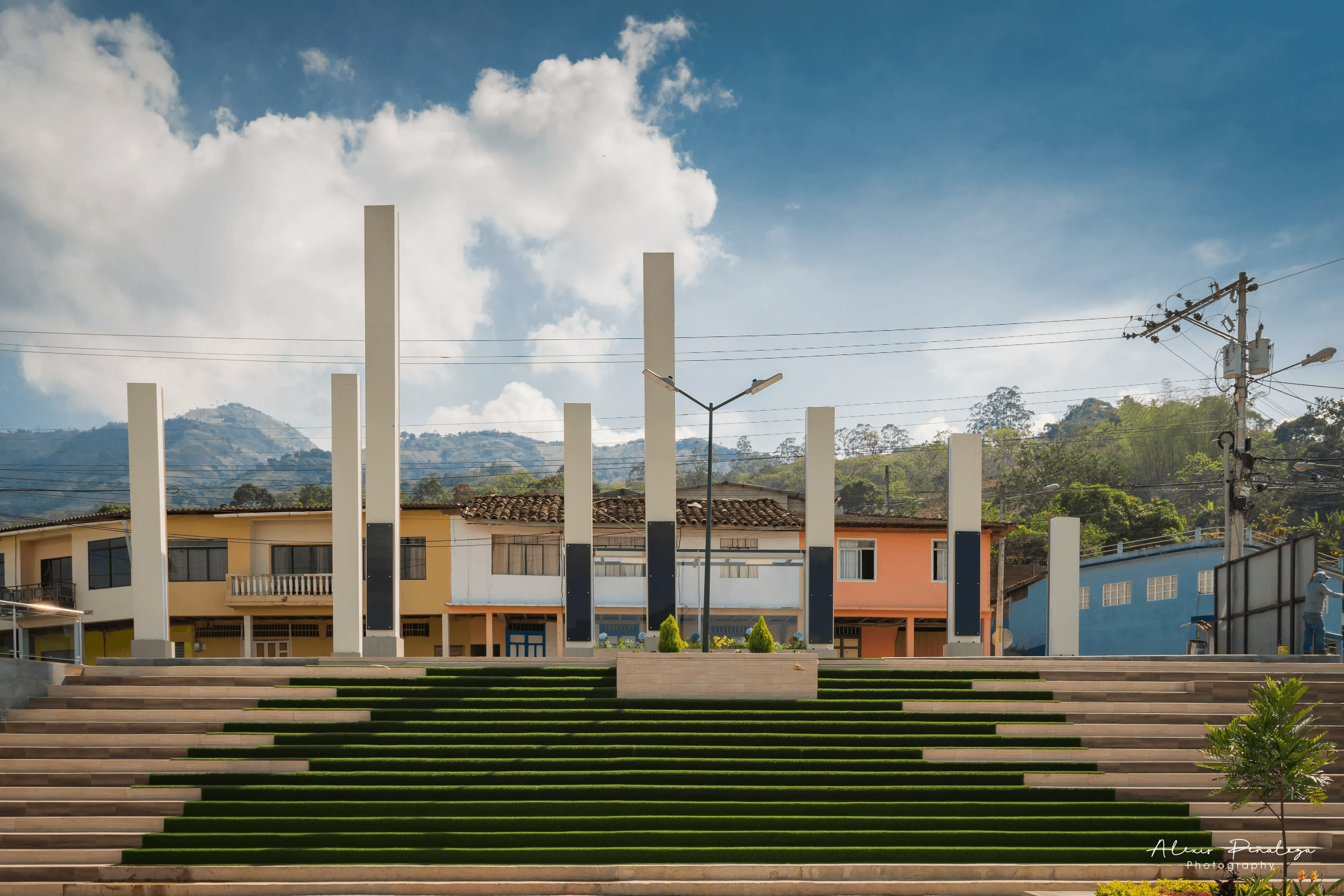 Vista frontal imponente del parque moderno escalonado con césped y altos pilares