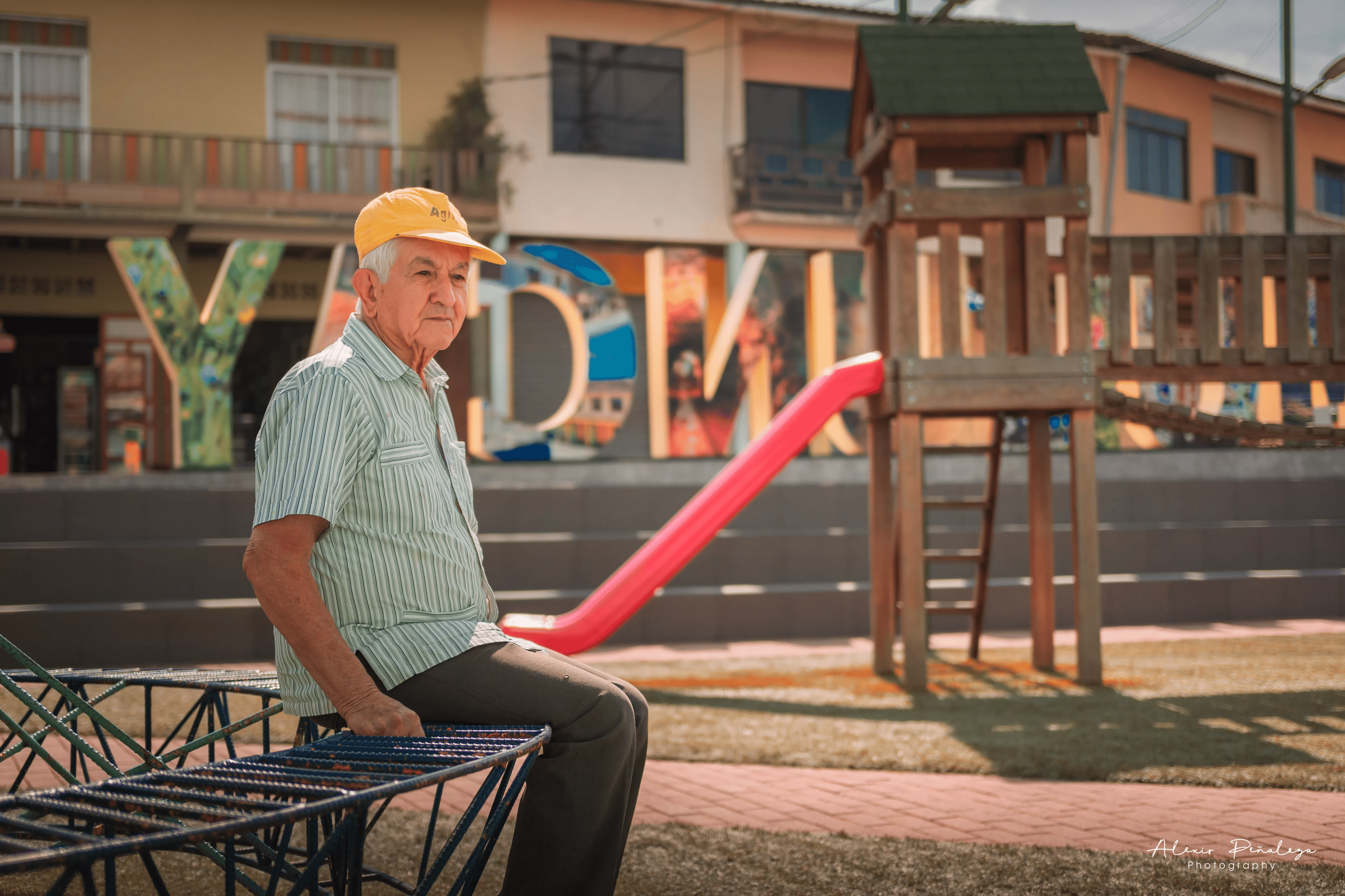 Señor descansando sobre el parque infantil enmarcado en el hermoso paisaje y el letrero
